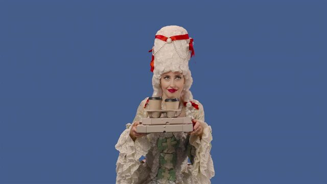 Portrait of courtier lady in white vintage lace dress and wig is holding cups coffee and boxes of pizza. Young woman posing in studio with blue screen background. Close up. Slow motion ready 59.94fps.