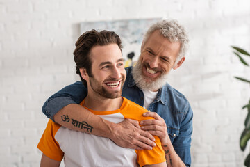 Mature dad hugging cheerful son in living room