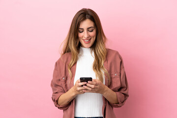 Caucasian woman isolated on pink background sending a message with the mobile