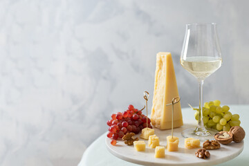 Wine tasting. Parmesan cheese, grapes, nuts and a glass of wine on a marble board. Appetizer. Parmigiano reggiano. Cheese plate. Wine card, rastaurant menu. Side view, copy space