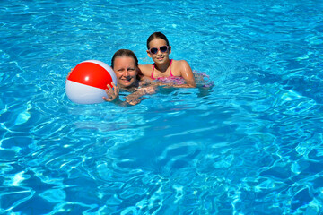 Female beauty relaxing in swimming pool with her daughter