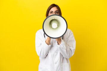 Doctor woman isolated on yellow background shouting through a megaphone