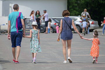 Parents with two girls walk along the city embankment