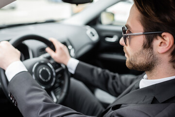 bearded man in sunglasses driving modern automobile