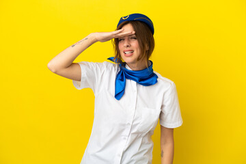 Airplane stewardess woman isolated on yellow background looking far away with hand to look something