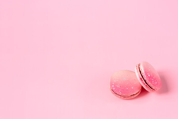 Pink macaroons on a pink background with a space for text. Sweet dessert for coffee and tea. Idea for postcards