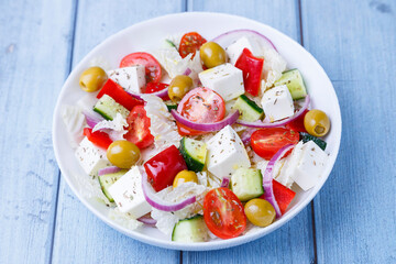 Greek salad. Traditional Greek dish. Healthy vegetarian food. Fresh vegetables and feta cheese in a white plate. Close-up.