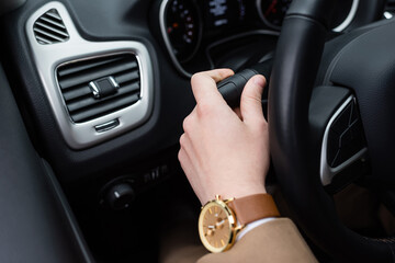 cropped view of man with wristwatch using turn signal while driving car