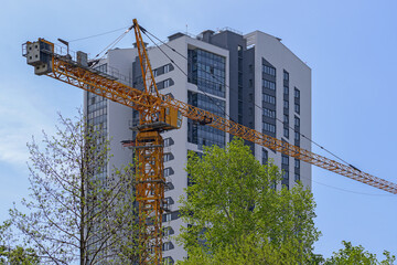 The top part of a construction crane on the background of a multi-storey building - Powered by Adobe