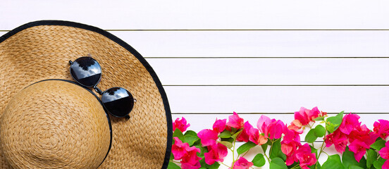 Summer hat with sunglasses and red bougainvillea flower on wood texture. Summer background concept.