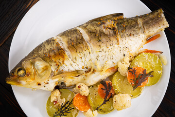 baked fish with vegetables on a wooden background. Top view with copy space