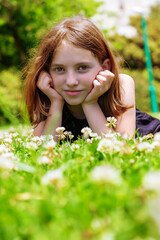 Naklejka na ściany i meble Beautiful emotional natural teenager girl lies in a meadow with flowers on a sunny day