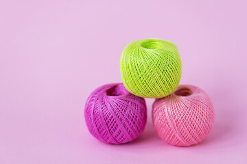 Skeins of thread for knitting on a pink background. Selective focus.