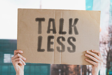 The phrase " Talk less " on a banner in men's hand. Human holds a cardboard with an inscription. Productivity. Percist. Stopping. Secret. Private information. Hidden