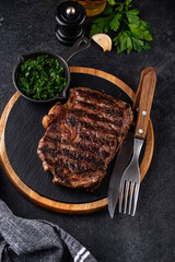 Grilled marbled rib eye steak with green sauce.