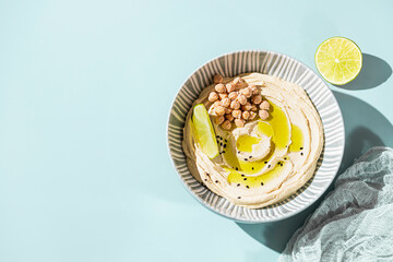 Chickpea hummus with olive oil and lime on a ceramic plate. Homemade classic hummus. Chickpea dishes, vegetarian dish.