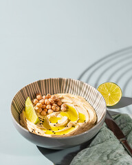 Chickpea hummus with olive oil and lime on a ceramic plate. Homemade classic hummus. Chickpea dishes, vegetarian dish.