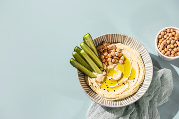 Chickpea hummus with olive oil and cucumbers on a ceramic plate. Homemade classic hummus. Chickpea dishes, vegetarian dish.