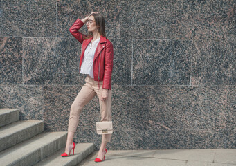 Beautiful fashion stylish woman with red jacket on the wall city background