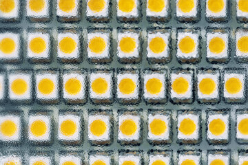 Close-up macro view of led smd bulb lamp with rows of yellow diode light components panel. Tech abstract texture pattern background electronic industry backdrop. Eco-friendly modern technology