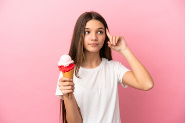 Little girl with a cornet ice cream over isolated pink background having doubts and thinking