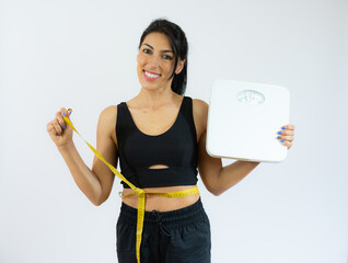 Smiling positive woman in black sports tights and top holding tape line on her waist and weight.