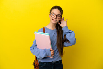 Fototapeta premium Student kid woman over isolated yellow background listening to something by putting hand on the ear