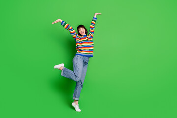 Full length photo of adorable cute young woman wear striped sweater smiling dancing isolated green color background