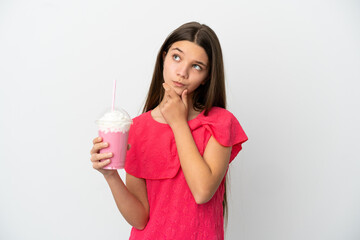 Little girl with strawberry milkshake over isolated white background having doubts