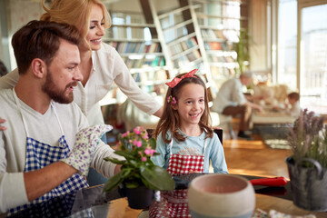 Little daughter enjoys planting at home with her parents. Family, leisure, together