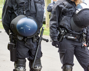 Uniformed German police officers with helmets, batons and knee pads