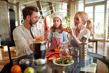 Mom and Dad enjoying preparing a meal with their little daughter at home. Family, together, home