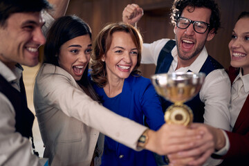 happy group of young businesspeople holding together the winning cup