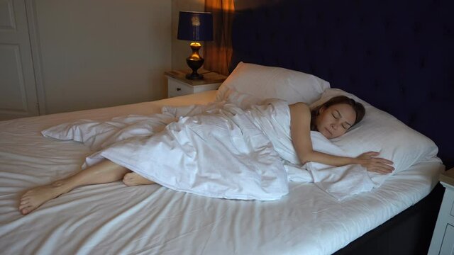 Female waking up. Young woman opens her eyes in luxury hotel bed. Happy young woman awake after healthy sleep on comfortable mattress, smiling girl fresh full of energy enjoying good morning get up.