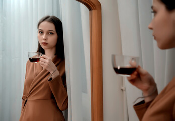 A young girl stands in front of the mirror with a cup of coffee.