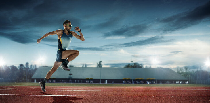 Professional male runner, jogger on stadium background. Caucasian fit athlete practicing, training excited