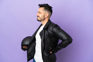 Young man with a motorcycle helmet isolated on purple background suffering from backache for having made an effort