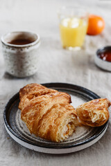 Breakfast with croissant, jam and hot chocolate, juice and tangerine on greige linen tablecloth. Selective focus - 434942057