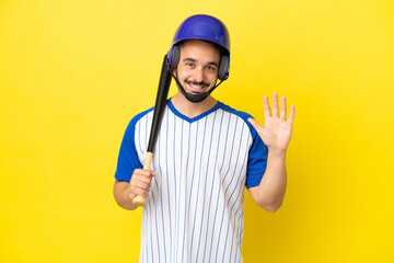 Young caucasian man playing baseball isolated on yellow background saluting with hand with happy expression