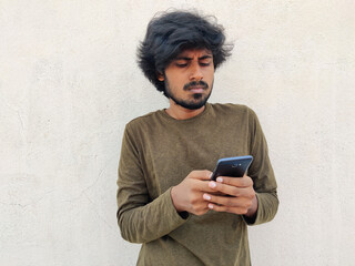 Fototapeta premium Serious looking south indian beard man using his smart phone. He is ordering something. White background