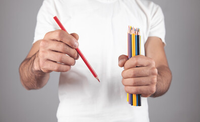 Caucasian man holding colored pencils.