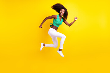 Fototapeta na wymiar Full length body size photo young girl jumping running laughing overjoyed isolated vibrant yellow color background