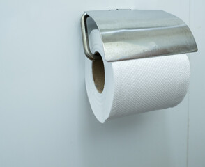 Close-up white paper towel (tissue) with stainless steel hanger on the bathroom wall.