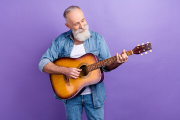 Photo of elderly handsome man happy positive smile play guitar concert isolated over purple color...
