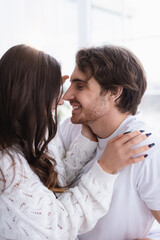 Smiling man looking at girlfriend in sweater at home