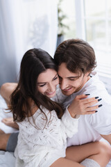 Smiling young couple hugging in bedroom
