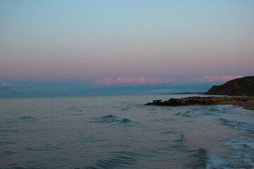 Obraz premium Azure sea with pink clouds from the sunset reflex on the horizon