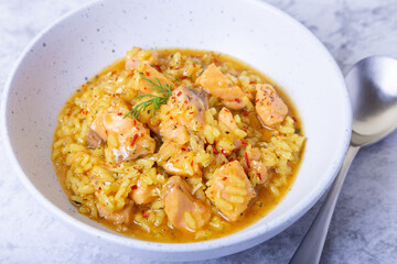Risotto with salmon and saffron in a white plate. Traditional Italian cuisine. Close-up.