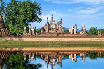 Fototapeta na wymiar Buddha statue and Pagoda in ruined monastery complex at Wat Mahathat temple with reflection, Sukhothai Historical Park, Thailand