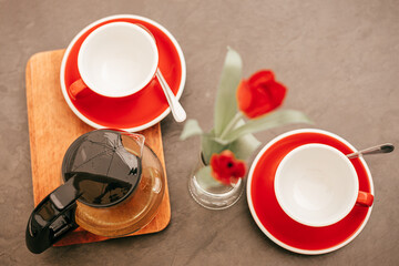 Flat lay, teapot with tea and two red empty mugs on a wooden table.